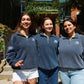 Three female OTD members in navy-blue Smith quarter-zips posing on the front steps of Goodes Hall